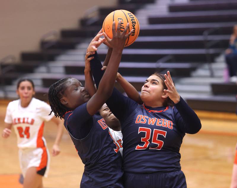 Oswego's Madelyn-Jordyn Mensah (left) and Nathalia Wheeler go after a rebound during their game Monday, Jan. 5, 2026, at DeKalb High School.