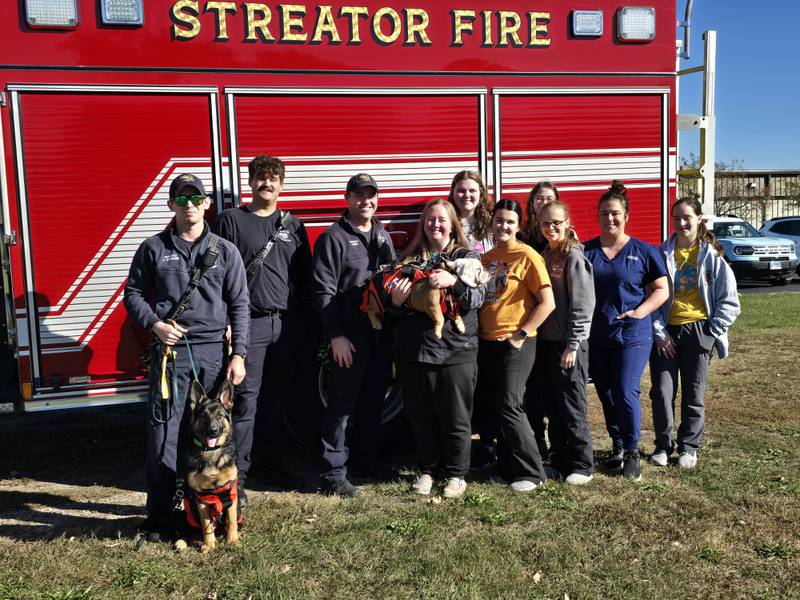 Streator firefighters thanked Countryside Animal Clinic on Thursday, Oct. 17, 2024, for a donation of three pet harnesses to assist in house fire responses. Pictured are (from left) Connor McMenamin with Echo, Andrew Cooke, Jeff Arendell, Dr. Abbie Eiten with Gladys, Kenzie Erschen, Marissa Grimm, Kaylee Maier, Danielle Ethington, Hollie Kolesar and Sydney Long.
