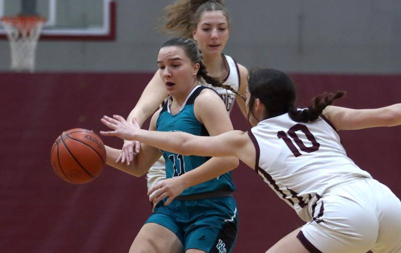 Woodstock North’s  Gracie Zankle, center, tries to get past Marengo’s Bella Frohling, right, and Gianna Almeida, back, in girls basketball at Marengo on Thursday.