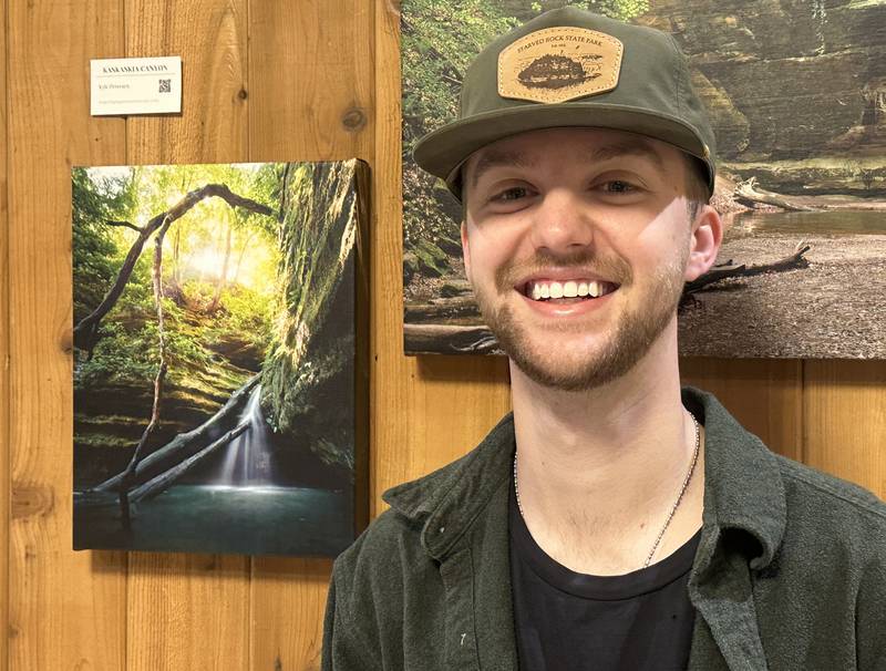 Kyle Petersen of Peru, poses next to his photo that he took of KasKaskia Canyon on Sunday, May 3, 2026 at the Starved Rock Visitors Center in Utica. Peterson has his work in the Starved Rock Foundation calendar and is part of Reel Creative.