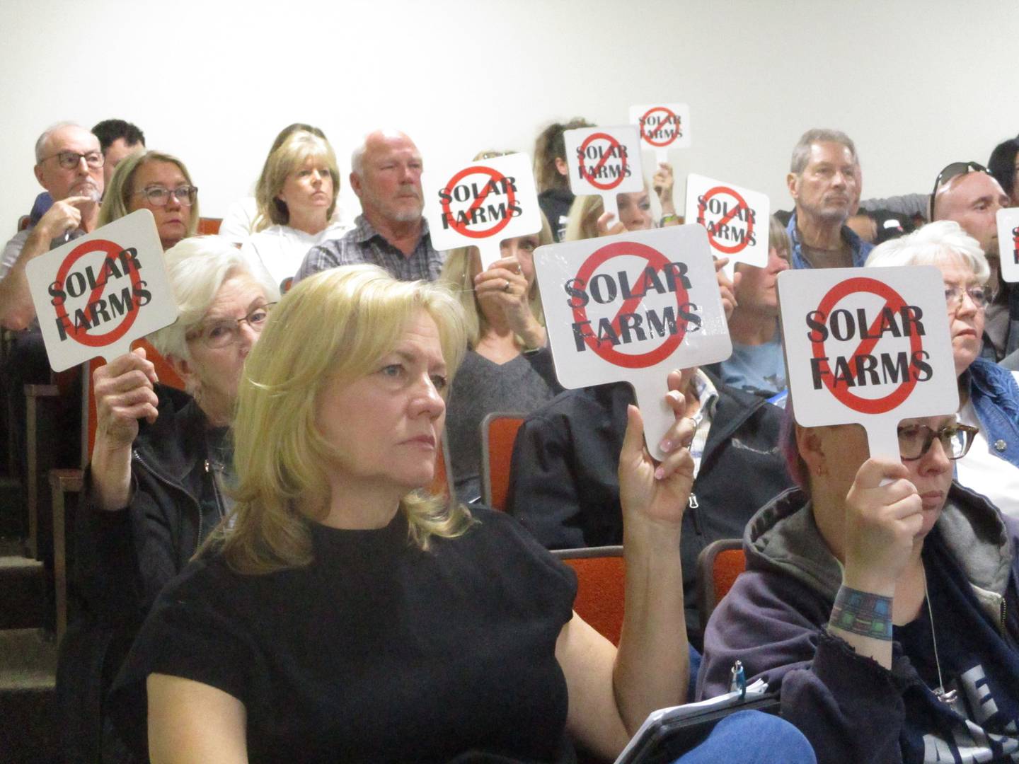 Opponents of the Pride of the Prairie solar project hold up signs at the Will County Board meeting on Thursday at the Will County Office Building in Joliet. May 21, 2026