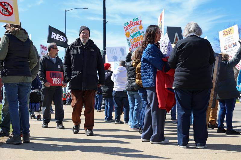 Ray Lescher, 90, a retired Catholic priest now of Hopkins Park, walks along the sidewalk of demonstrators during the No Kings rally at the Kankakee County Courthouse on March 28, 2026. Lescher, a longtime Kankakee-based priest, participated in protests at the same location 65 years ago during the civil rights movement. 
“It’s the same cause today- justice and human rights,” he said. “[We’re] standing up for justice from a different angle.”