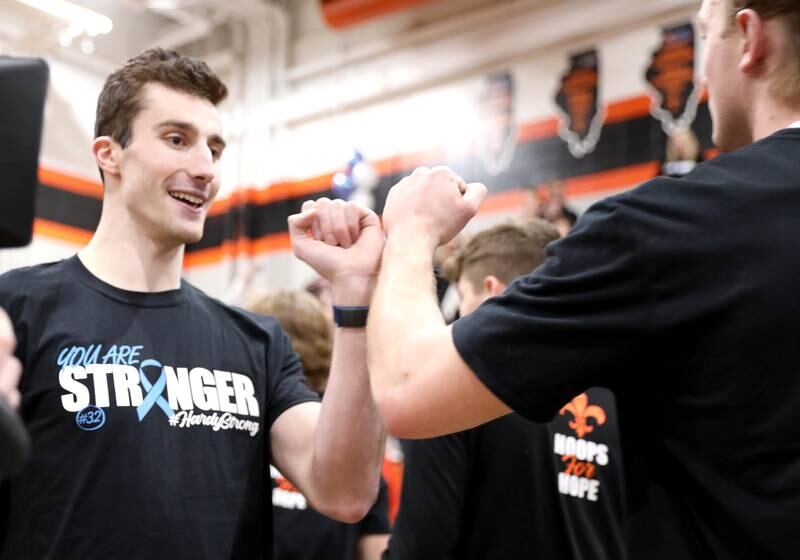 Justin Hardy, a former St. Charles East four-year varsity basketball player and current player for Washington University in St. Louis, high-fives current East players during a Hoops for Hope game in Hardy’s honor against Geneva in St. Charles Tuesday, Feb. 8, 2022. Hardy was diagnosed with Stage IV stomach cancer last April and continues to play basketball while undergoing treatment.