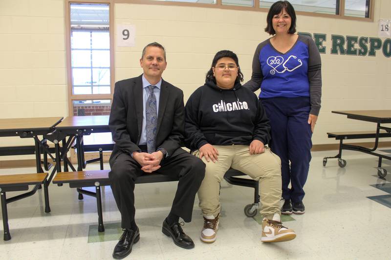 Aux Sable Middle School Principal Christian Rivara (left) and school nurse Shannon Morris flank sixth-grader Sergio Escobedo at the lunch table where Sergio saved his friend from choking. Sergio said he learned the Heimlich maneuver from YouTube and social media.