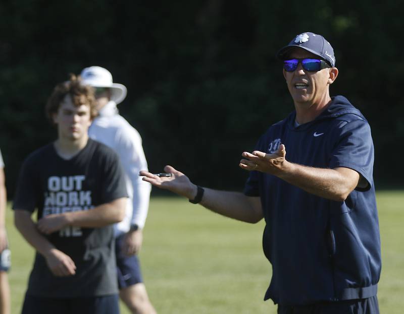 Cary-Grove Coach Brad Seaburg explains their play calling to players during summer football practice Thursday, June 30, 2022, at Cary-Grove High School in Cary.