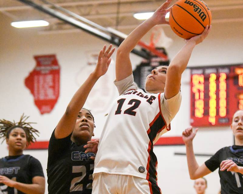 Yorkville's Hayden Hodges (12) goes up and makes a basket while getting fouled by Oswego East's Inspire Fisher (23) during the game on Thursday Dec. 18, 2025, held at Yorkville High School.