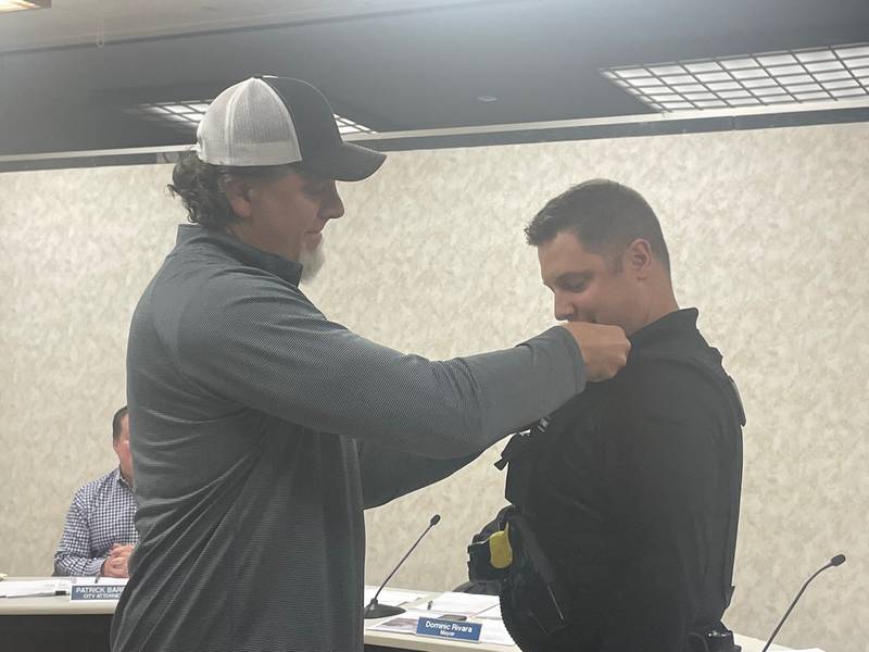 Before a packed house Monday, Oglesby Officer Evan Duttlinger (right) was promoted to sergeant. His sergeant’s badge was pinned to his uniform by his uncle, retired Sgt. Rick Piscia.