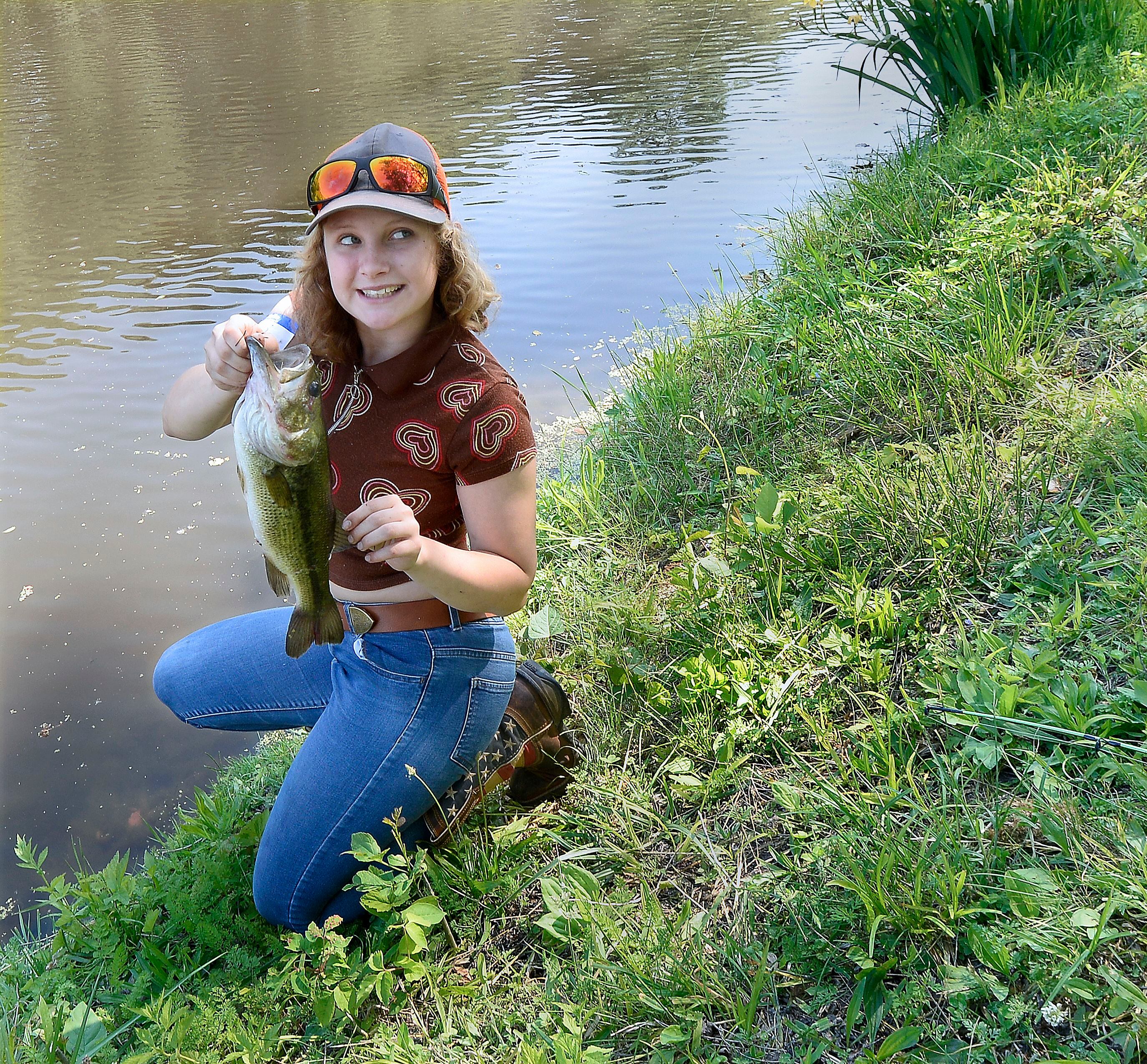 LeAnn Oleson shows the other anglers along the bank of the canal her 15-inch bass she pulled in Saturday, June 3, 2023, during the 36th annual Kid's Fishing Tournament at Lock 14 in La Salle.