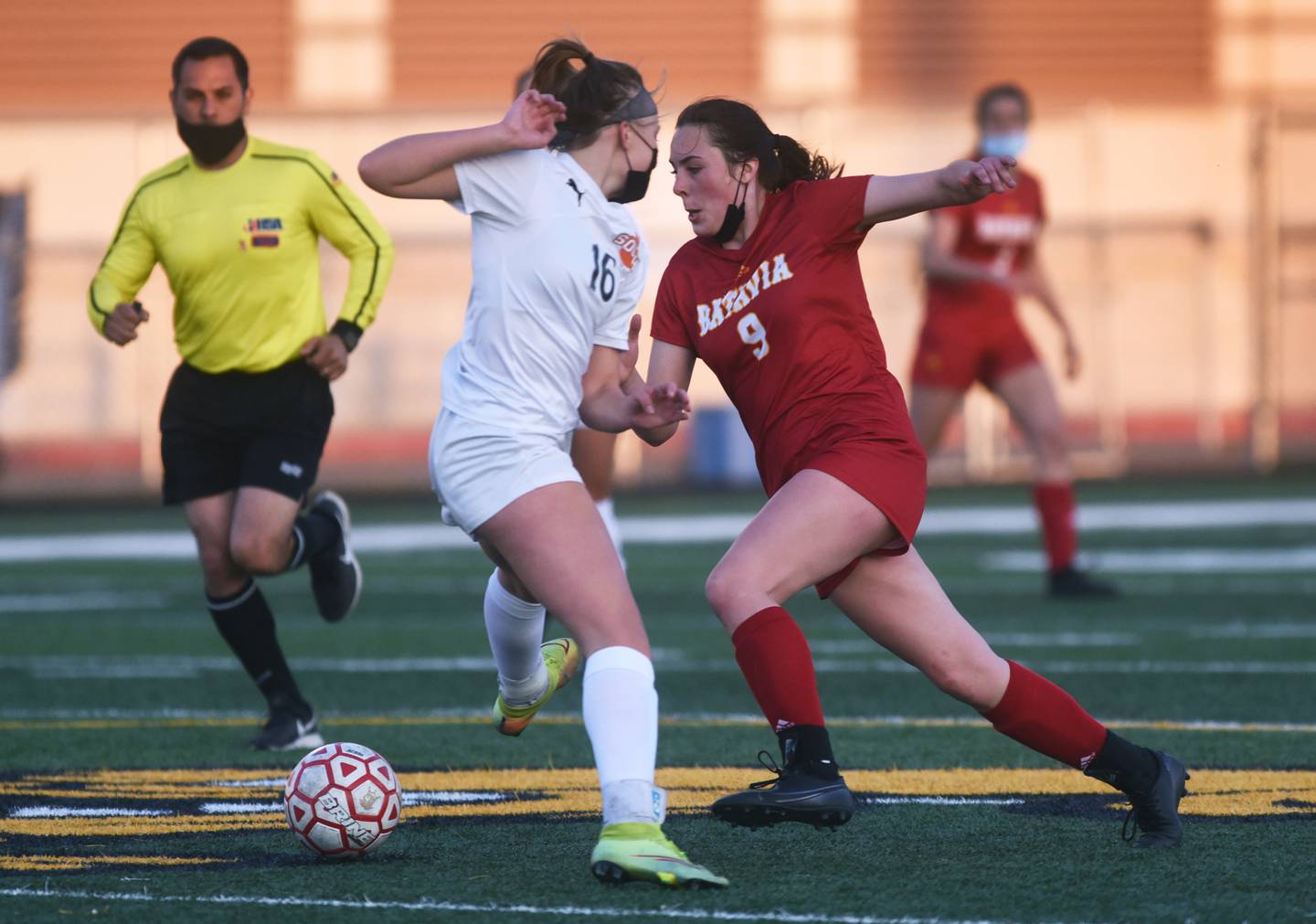 Batavia's Ashley Whelpley (9) guides the ball past Wheaton Warrenville South's Elise Farrell (16) during Thursday's girls soccer game in Batavia.