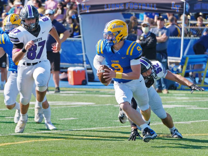 Lyons Township quarterback Ryan Jackson (9) scrambles away from Downers Grove North's Alexander Kartsounes (52) and Vincent Lewis (87) during a game on Oct. 22, 2022 at Lyons Township High School in LaGrange.