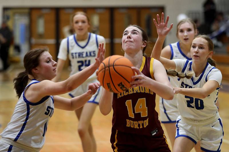 Richmond-Burton's Lilly Kwapniewski (center) shoots the ball between Woodstock's Emma Douglas (left) and Kendall O'Dea (right) during a Kishwaukee River Conference girls basketball game on Wednesday, Jan. 28, 2026, at Woodstock High School.
