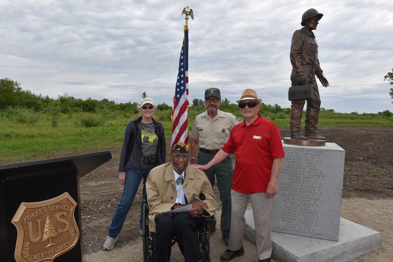 (Left to right): Midewin Volunteer Penny Vanderhyden; former Joliet Arsenal worker and Joliet Arsenal Advisory Board member Elmo Ray Younger;  USDA FS Archaeologist (Midewin) Joseph Wheeler; and Wendell Johnson gather around a statue at Midewin National Tallgrass Prairie that is dedicated to arsenal workers. This summer, USDA FS employees and volunteers hosted a public program at Midewin to honor the arsenal workers.
