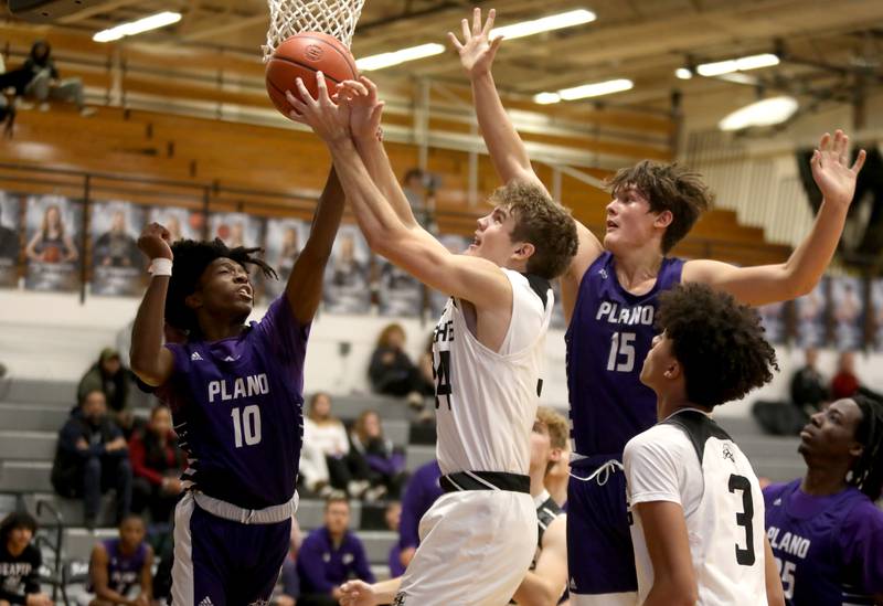 (Right to left) Plano’s Davione Stamps, Kaneland’s Parker Violett and Plano’s Kaleb Videckis go up for a rebound during a game in Maple Park on Tuesday, Dec. 20, 2022.