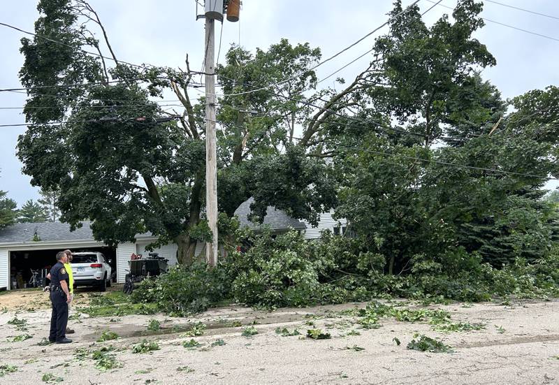 Byron Police Chief Jeremy Boehle and a city worker survey storm damage on Colfax and W. Second streets in Byron, on Tuesday, July 16, 2024. A strong storm ripped through the town Monday night felling trees, damaging homes, and knocking out electrical service.