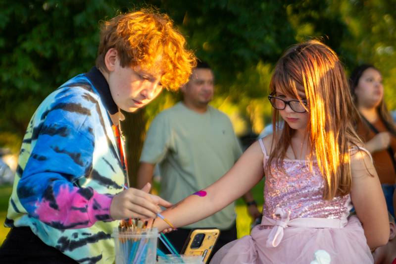 Allyssah Arteaga paints Analysia Neilsen’s arm Friday, Aug. 23, 2024, at Family Safe Night at the Mendota Civic Center.