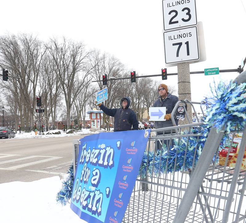 Matt Urback and Mike Corrigan hold signs during the 17th annual Freezin’ for a Reezin’ event on Friday, Dec. 5, 2025 at the intersection of Lafayette Stret and Illinois Route 23 downtown Ottawa. Donations support the Community Food Basket of Ottawa. Freezin’ for a Reezin’ featured nterviews with local celebrities, musical performances by several Ottawa school choirs and bands and, of course, the giving.
