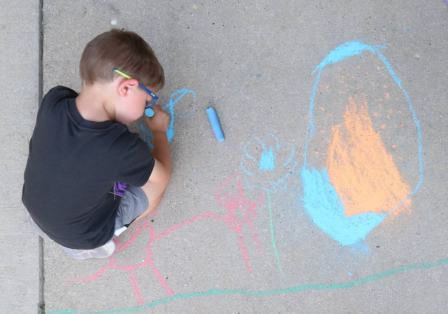 Collin Caputo colors the sidewalk in front of the Peru Public Library during their "Chalk the Walk" event on Tuesday, Aug. 13, 2024.
