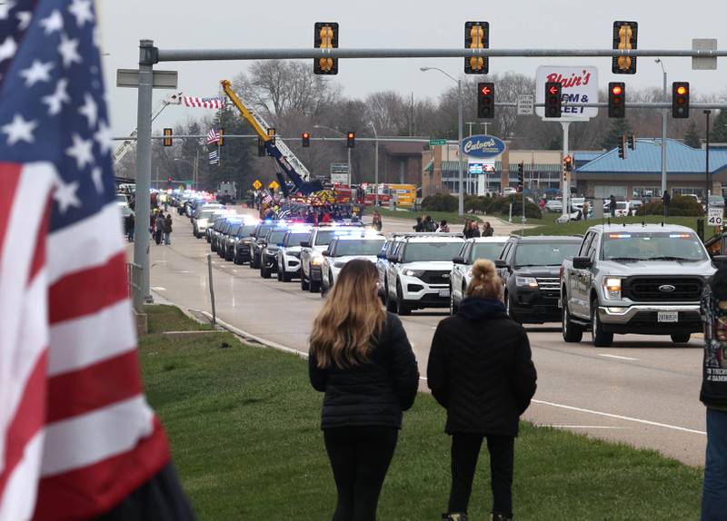 The processional honoring DeKalb County Sheriff’s Deputy Christina Musil travels through people lining the route Monday, April 1, 2024, on DeKalb Avenue in Sycamore. Musil, 35, was killed Thursday while on duty after a truck rear-ended her police vehicle in Waterman.