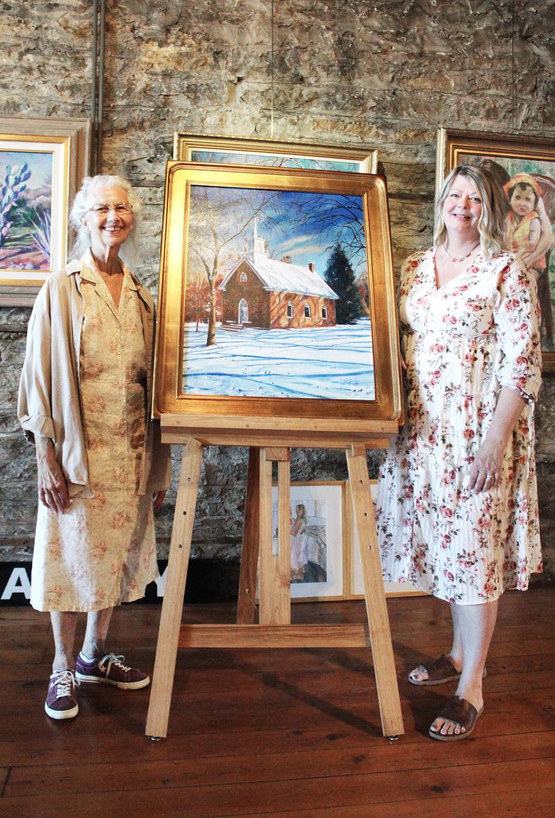 Grand Detour artist Jane Edgar (left) will sell her 2003 painting of St. Peter Episcopal Church in Grand Detour during the 75th annual Grand Detour Arts Festival on Sept. 8. She is pictured with The Next Picture Show executive director Letha Catalina. Edgar and her husband Ralph founded TNPS in 2004, and she has her works displayed in the downtown Dixon art gallery's second floor.