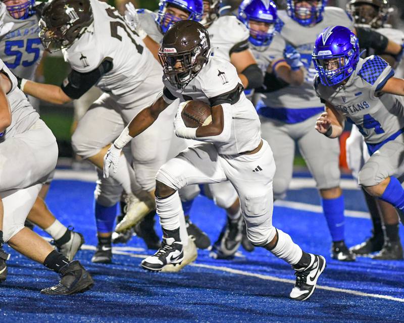 Joliet Catholic Academy’s HJ Grigsby, center, runs the ball for a touchdown during the first quarter on Friday Sep. 22, 2023, while traveling to take on St. Francis in Wheaton.
