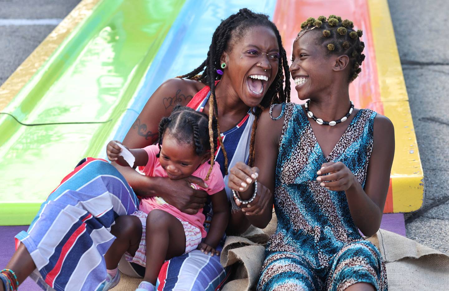 Mariyah Ofei, (left) and her daughter Jahnora Sturges, 2, along with Haniyyah Woods, (right) all from DeKalb, have some fun riding the slide in the carnival area Friday, Aug. 26, 2022, during Corn Fest in downtown DeKalb.