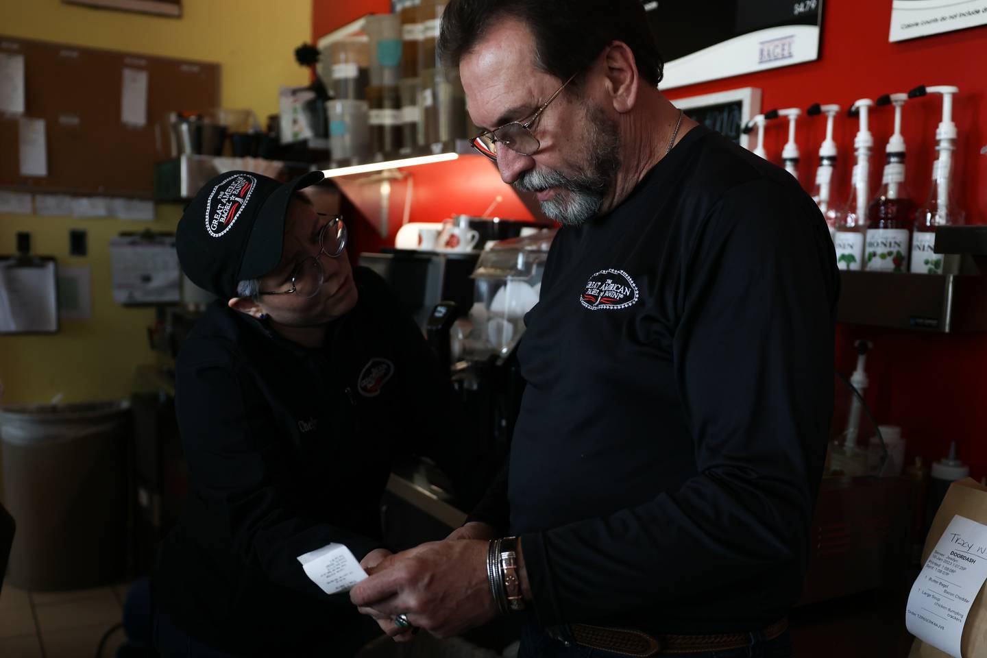 Tom Grotovsky, owner of Great American Bagel, looks over an order with Chely Castillo at his Joliet location on Essington Road.