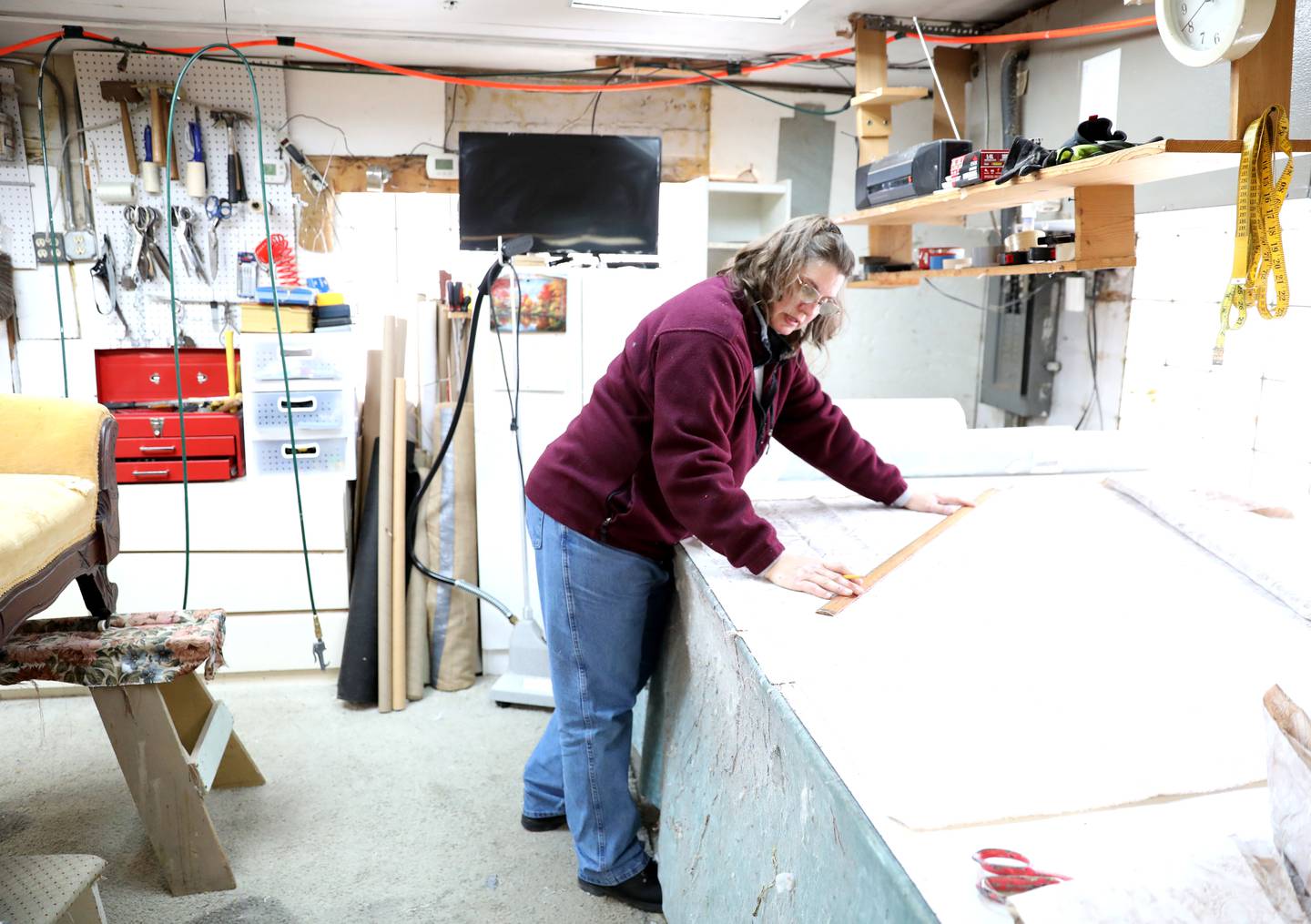 Ruth Scott cuts fabric at Valley Upholstery and Design in Batavia. Following the September 2021 death of Valley Upholstery and Design owner Jesse Pitts, his family and friends, including daughter Jesseca Watson, wife Eloise and friend Ruth Scott, have been working diligently to complete his customers’ projects and keep the shop open.