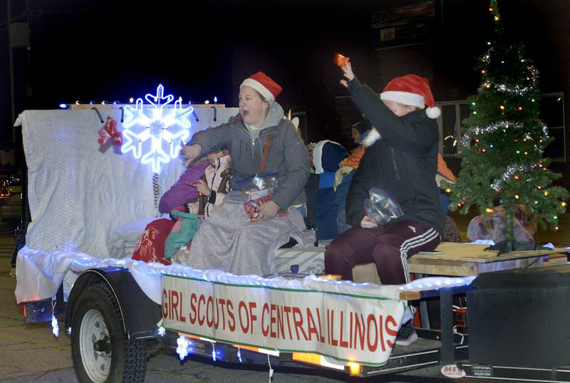 Those upon the Girl Scouts Of Central Illinois float toss candy treats to those along Main St in Marseilles Saturday during the annual Holiday Magic Lighted Santa Parade in Marseilles.