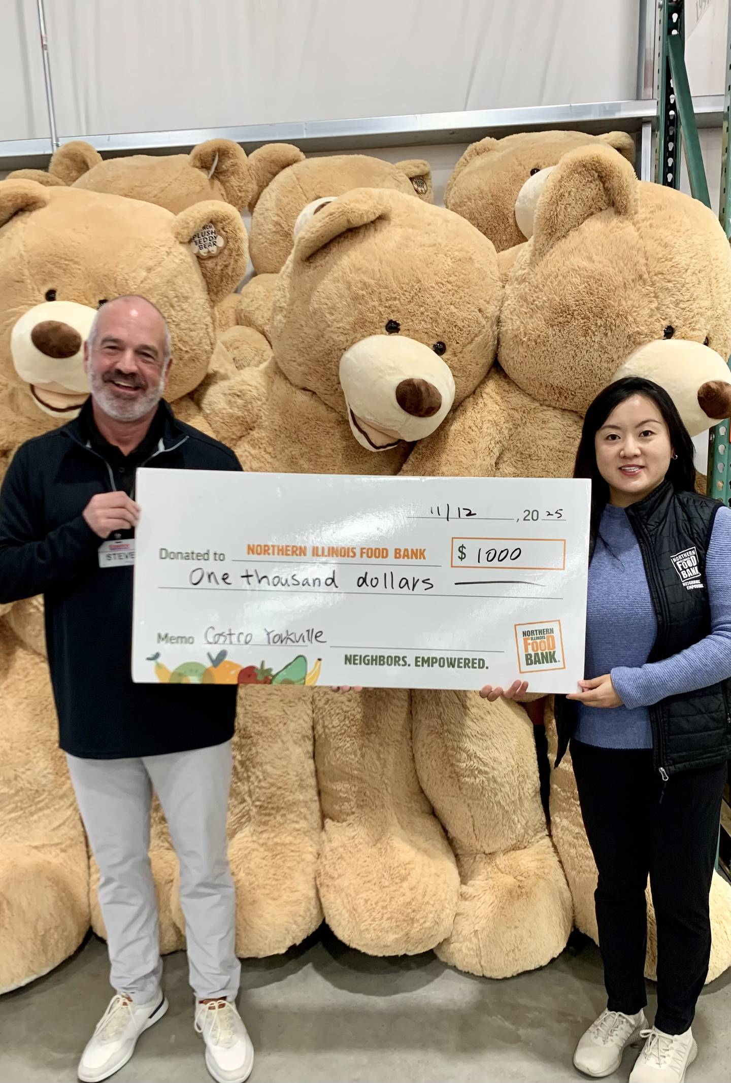 Steve Ftacek, general manager of Costco Yorkville, donates $1,000 to the Northern Illinois Food Bank. Summer Zhao (right) said the money will pay for $8,000 worth of groceries for Kendall County neighbors in need.