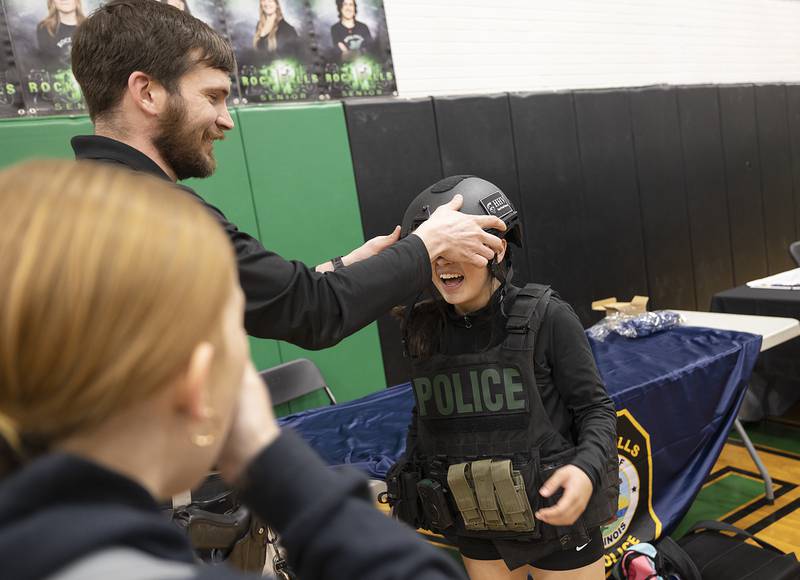 Rock Falls High School freshman Regina Ramirez tries on Ethan Riley’s helmet Thursday, March 6, 2025, during the college and career fair at RFHS. Riley, the school resource officer, set up a booth to talk to students about a career as a police officer.