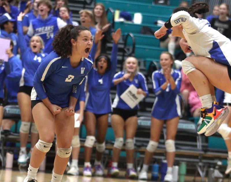 Woodstock’s Ava Sieck, left, gets the Blue Streaks hyped up late in the second set of a two-set win over rival Woodstock in varsity volleyball at Woodstock North Monday night.