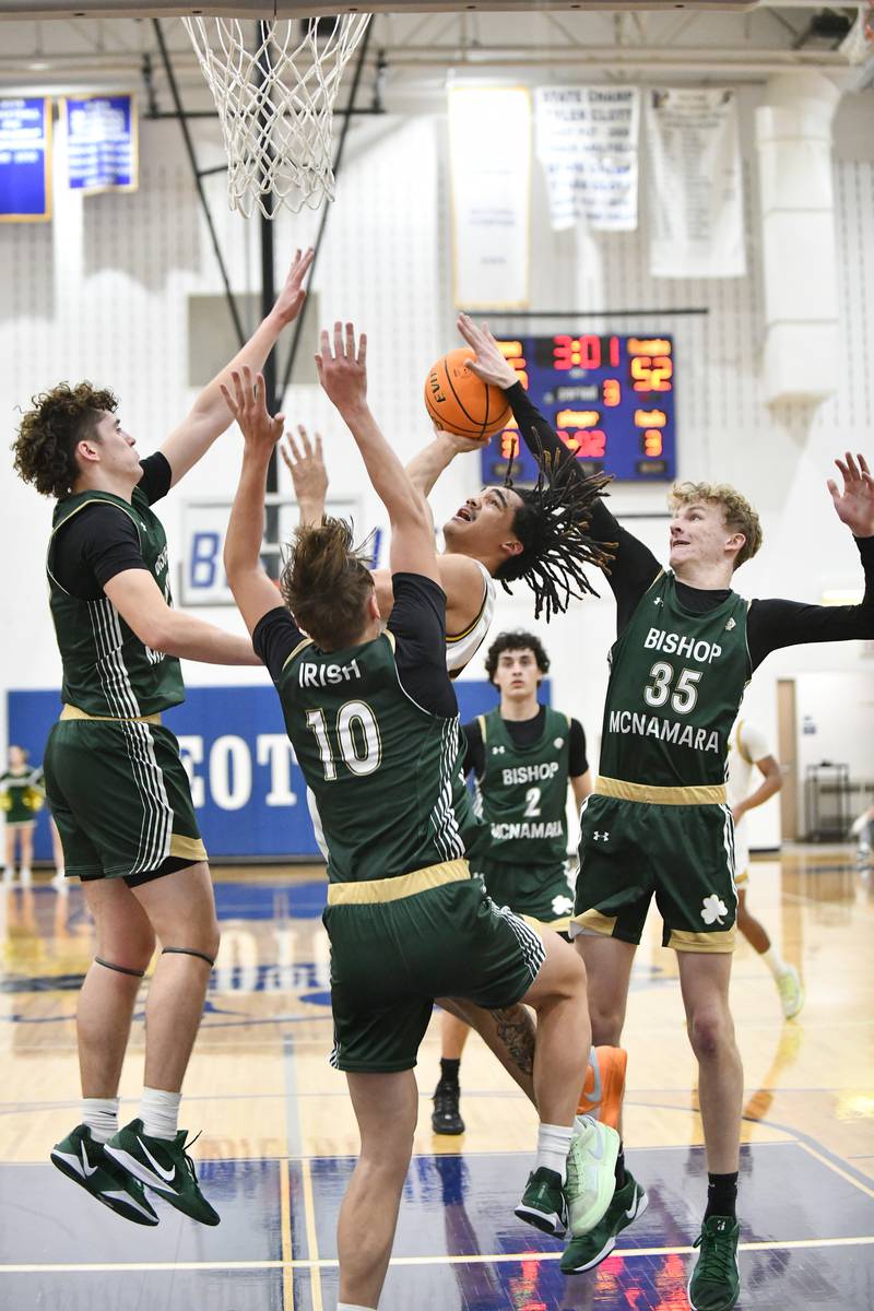 Joliet Catholic Academy's JJ Sterrett attempts a shot under pressure from Bishop McNamara defenders during the Fightin' Irish's 79-67 victory over the Hilltoppers in the IHSA Class 2A Peotone Sectional semifinal on March 4, 2025.