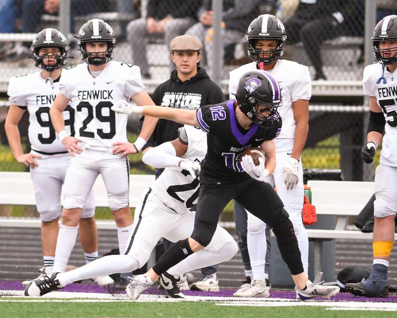 Downers Grove North's Max Troha (12) gains enough yards for a first down before being pushed out of bounds by Fenwick's Josh Morgan (26) during the second week of the class 7A game on Saturday Nov. 9, 2024, held at Downers Grove North High School.