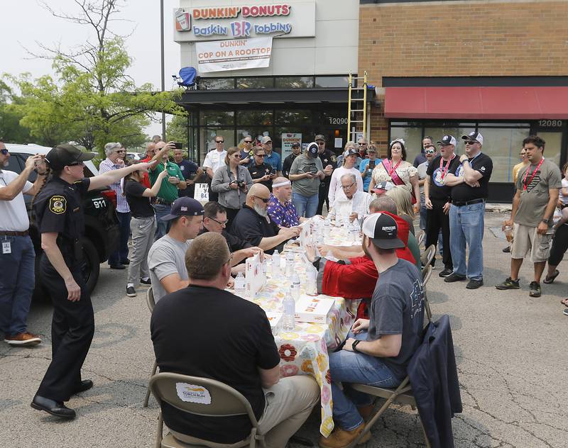 Donut eating contestants open their boxes of donuts and start the eating after being started by Special Olympians at Dunkin’ Donuts, in Huntley, during the Cop on a Rooftop fundraiser to raise awareness for Special Olympics Illinois and the Law Enforcement Torch Run to benefit Special Olympics on Friday, May 19. 2023.