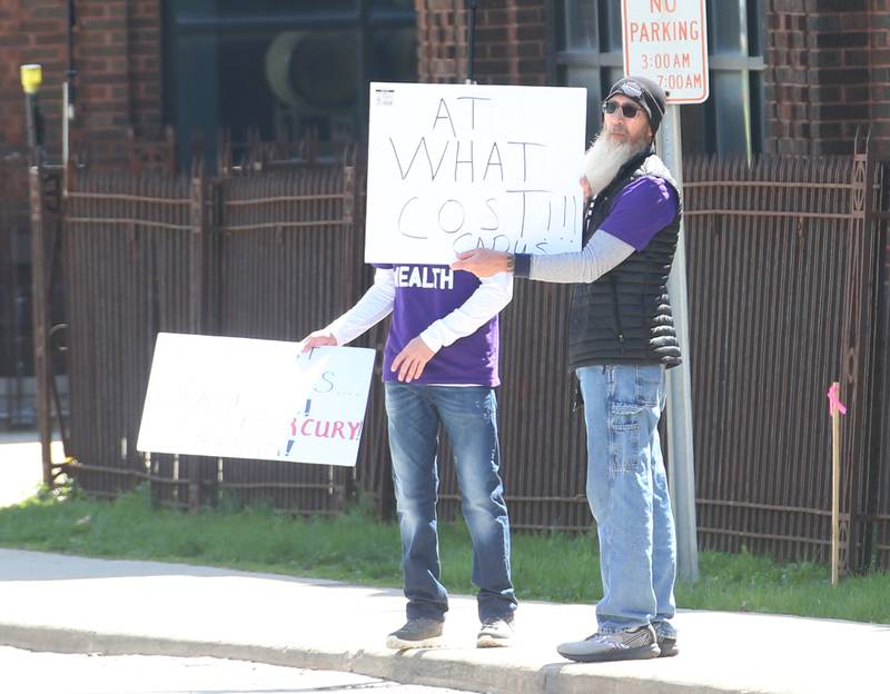 La Salle resident Jamie Hicks holds a sign that reads "At What Cost" while attending "Protest Carus Negligence" outside Carus headquarters across from the Westclox building on Friday, April 21, 2023 in Peru.