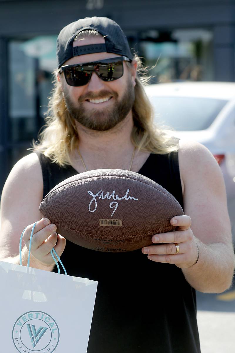 Marshall M”Lady, of Crystal Lake, shows off is football signed by former Bears quarterback Jim McMahon during the grand opening of the Vertical Dispensary on Saturday, Sept. 30, 2023, in Cary. The dispensary has been open for about a month.