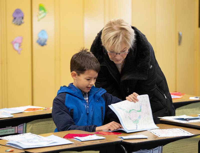 2nd-grader Calvin VanCura shows his grandma Gail Frantz work he’s done in class during Saint Mary of Gostyn School's Open House in Downers Grove on Sunday, Jan. 29, 2023.