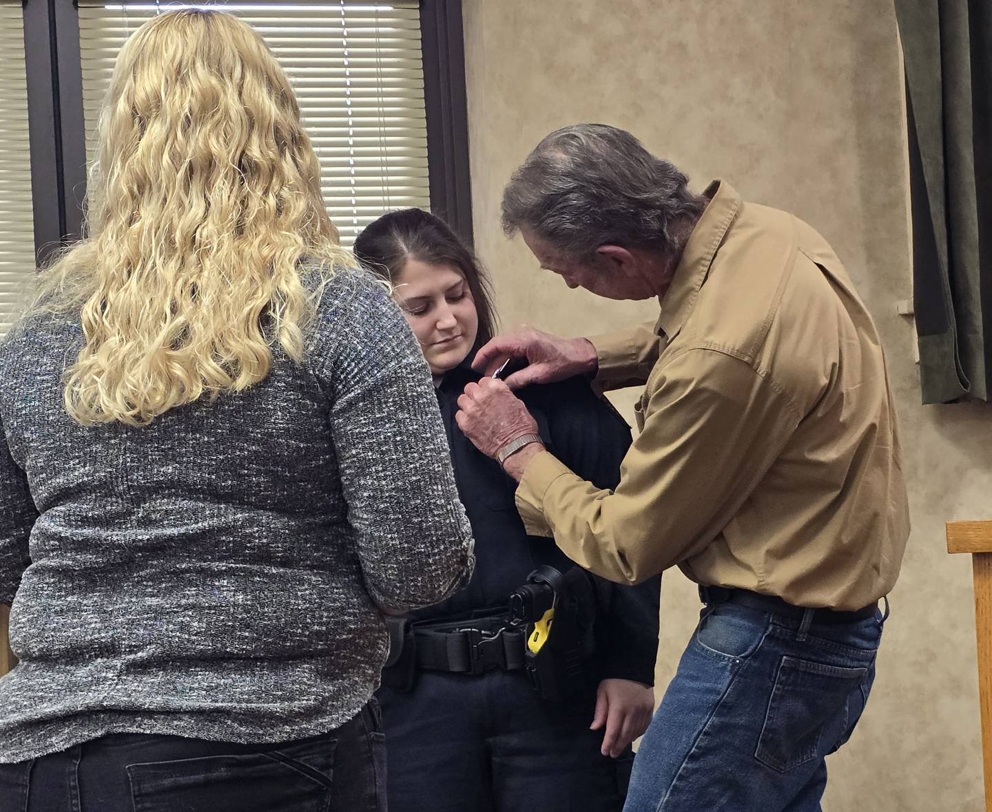 Princeton Police Officer Taylor Wetsel gets her badge put on her uniform by family members Monday, May 5, 2025, at Princeton City Hall.