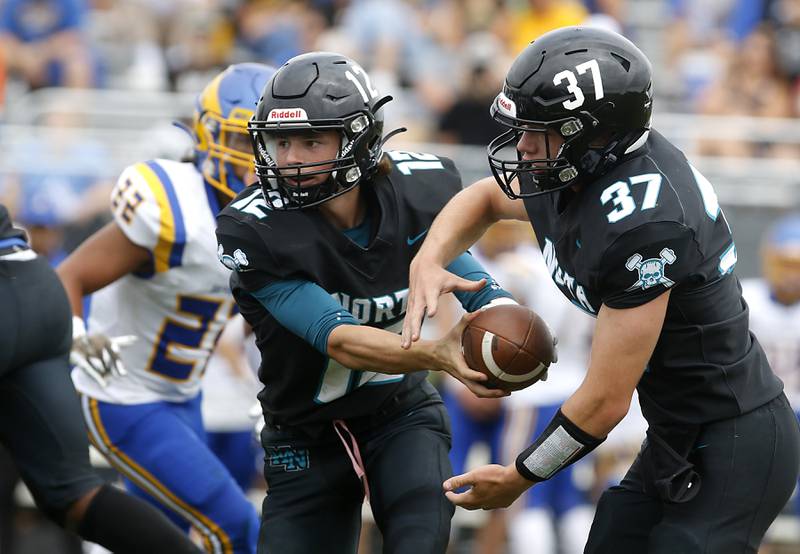 Woodstock North's Landan Creighton hands the ball off to teammate, Kaden Combs, during a Kishwaukee River Conference football game aagainst Woodstock North Saturday, Aug. 26, 2023, at Woodstock North High School.