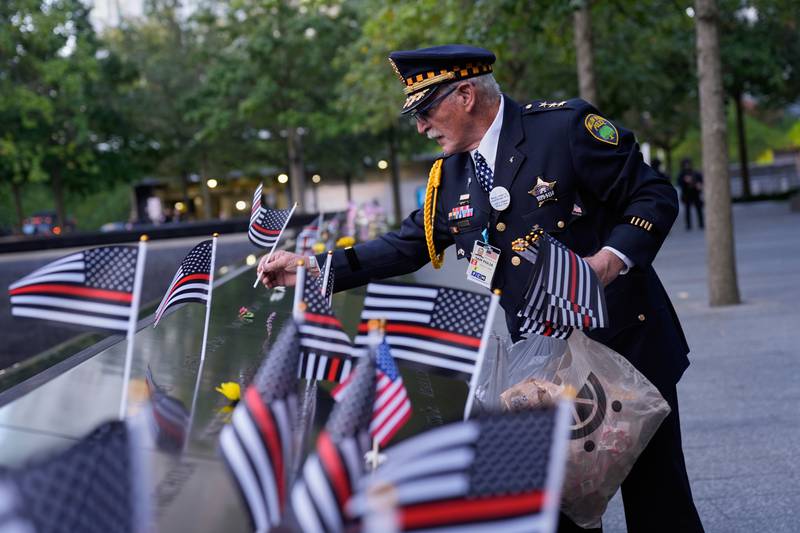 Sam Pulia places flags on names inscribed in the 9/11 Memorial before the start of a ceremony commemorating the 24th anniversary of the Sept. 11, 2001, attacks, Thursday, Sept. 11, 2025, in New York.  (AP Photo/Seth Wenig)
