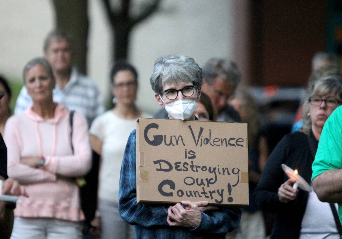 Roxanne Curtis of Batavia holds a sign during a candlelight vigil Wednesday, July 6, 2022, at the Kane County Courthouse in Geneva. The vigil was called to join in solidarity in honor of the mass shooting at a Fourth of July parade in Highland Park.