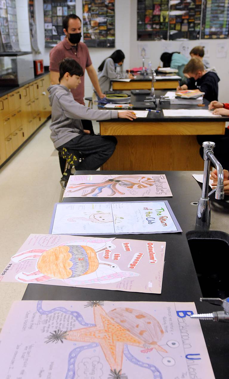 Science teacher Brian Sanford talks with student Morgan Smith, 13, on Tuesday, March 22, 2022, as he teaches seventh-grade science at Algonquin Middle School. Sanford, who bring art and games into the classroom to help teach science, has asked the students to draw monster movie posters as part of the current science study unit.