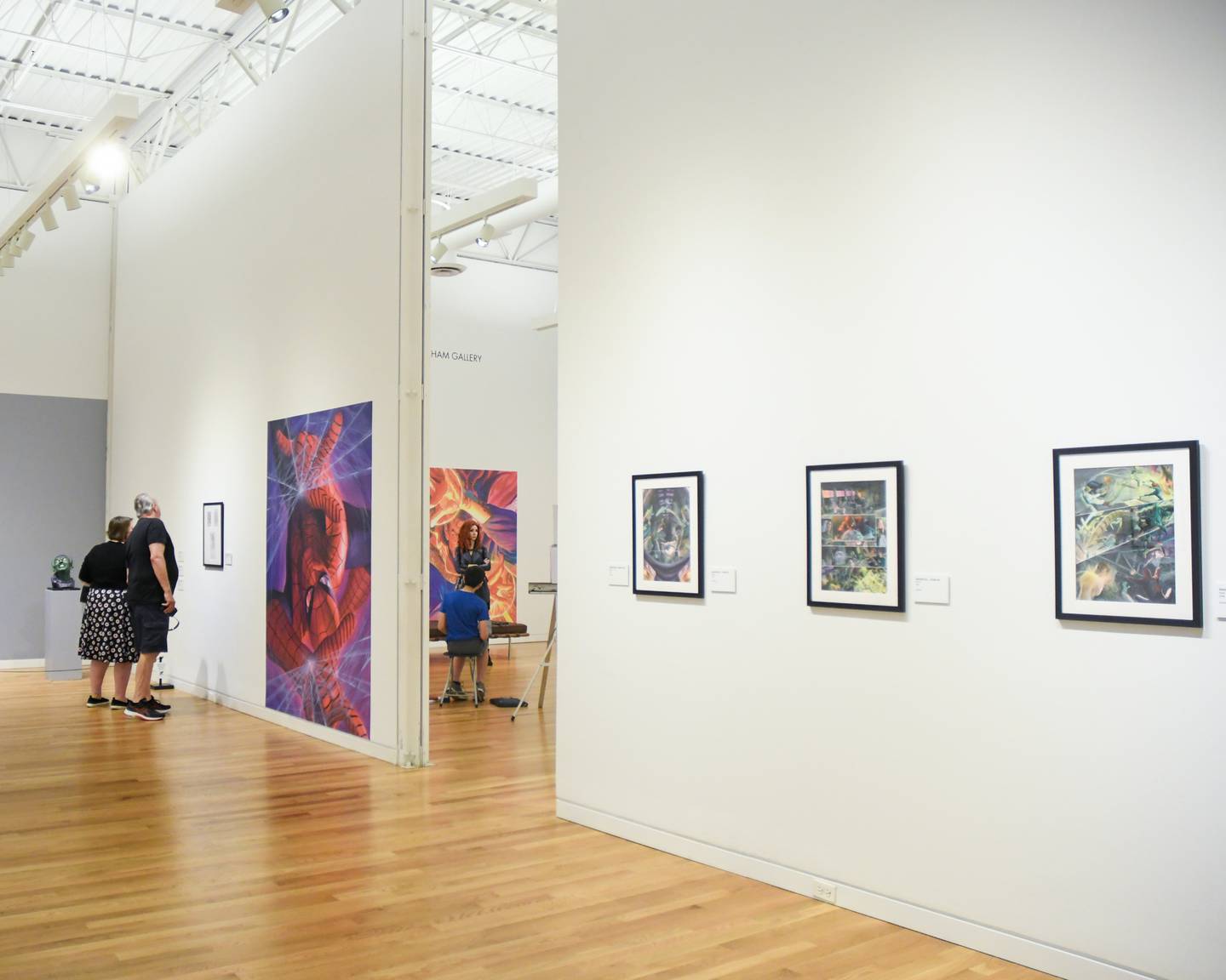 Valerie Panos and her husband Tony Gronowski of Downers Grove look at the artwork on display at the Elmhurst Museum as Lisa J. portrays the Black Widow as part of a live model demonstration, in the next room, that was all part of the Marvelcity: exhibit that took place on Saturday June 24, 2023.