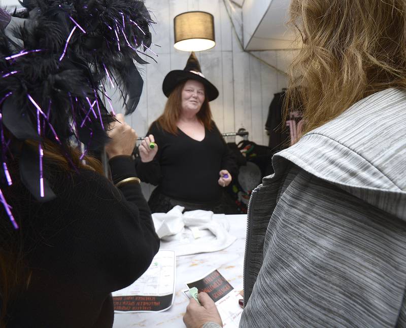 Thread Revival owner Rhonda Hensley marks a bingo card for participants in the Streator Chamber sponsored Halloween Spooktacular scavenger hunt Friday night.