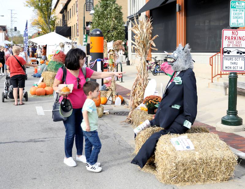 Debbie Krueger of St. Charles and her grandson, Dominic, 5, look at a scarecrow on display along Riverside Avenue on Friday, Oct. 11, 2024 during Scarecrow Weekend in downtown St. Charles.