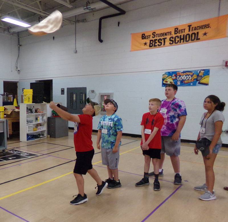 A young chef tosses a fake pizza dough used for training purposes Wednesday, June 22, 2022, at Northlawn School during the Illinois Junior Chefs program led by the University of Illinois Extension office.