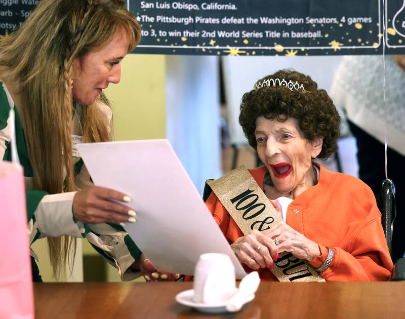 Rachel Lawson, executive director of Heritage Woods of DeKalb, presents resident Claire Hubele a birthday card signed by other residents Wednesday, July 9, 2025, during a party celebrating her 100th birthday.
