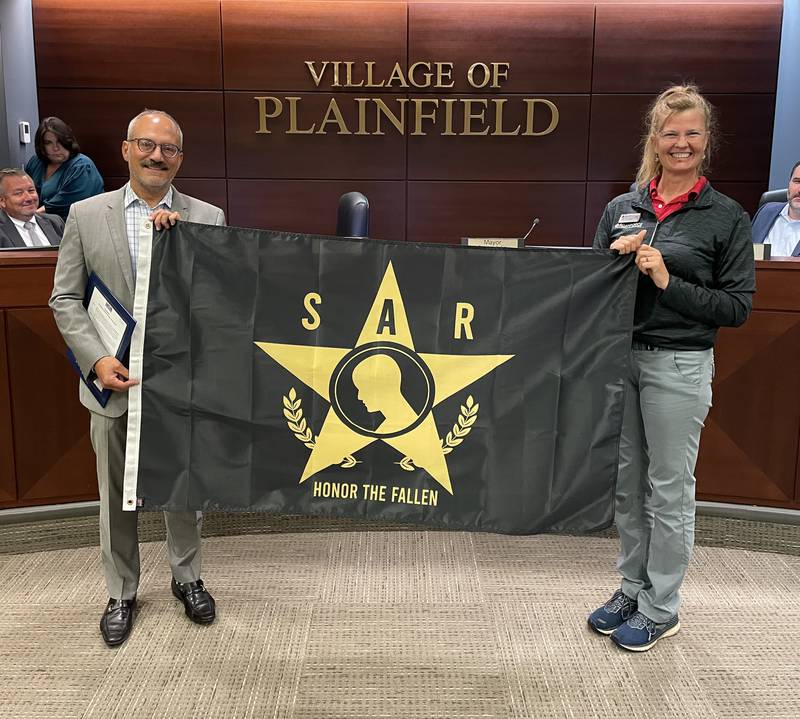 Mayor John Argoudelis and Donna Allen Rielage, founder and chief executive officer of AllenForce in Plainfield, hold the suicide awareness flag AllenForce commissioned for its fundraiser and memorial ceremony on Sept. 17, 2022. The village will fly the flag for one week in September.
