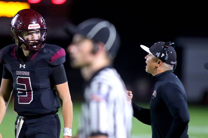 Marengo’s Head Coach Paul Forsythe, right, gives direction to quarterback Sam Vandello against Johnsburg in varsity football at Rod Poppe Field on the campus of Marengo High School in Marengo on Friday, Oct. 3, 2025.