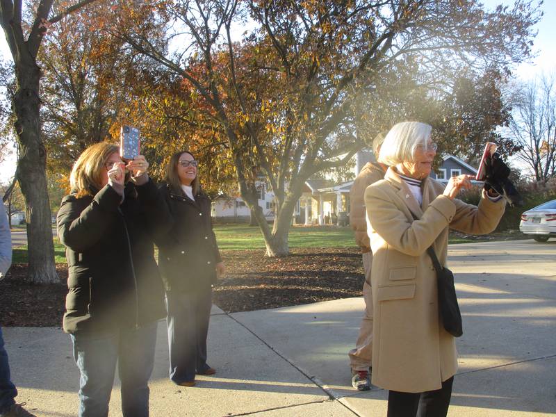 Darra Glavin (front) takes photos and video of the family tree being cut down in her yard to be used for the city of Joliet's annual Christmas tree. Nov. 14, 2025